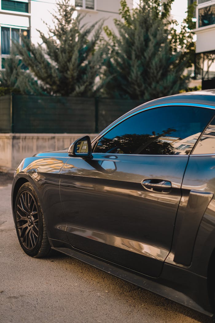 Close-up of a black sports car with tinted windows parked outdoors.