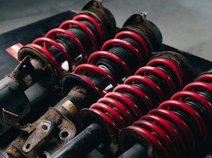 Close-up image of red coilover suspensions with a black background, ideal for automotive or mechanical themes.